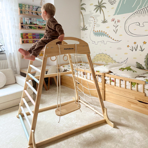 Puinen sisäleikkipuisto, jossa on keinu, voimistelurenkaat ja kiipeilyverkko